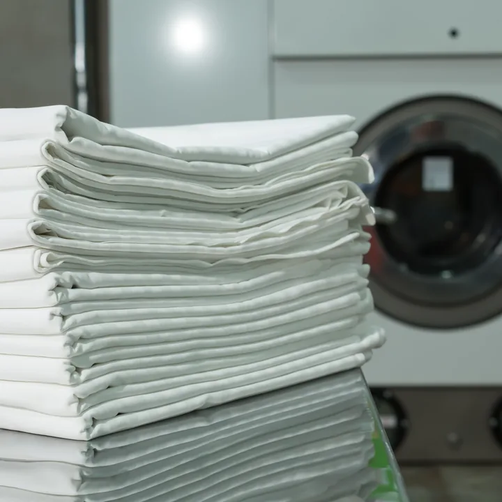 Gefaltete Wäsche vor einer Profi-Waschmaschine